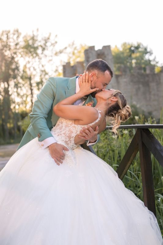 Le marié embrasse la mariée renversée en arrière, devant les remparts d'un château fort