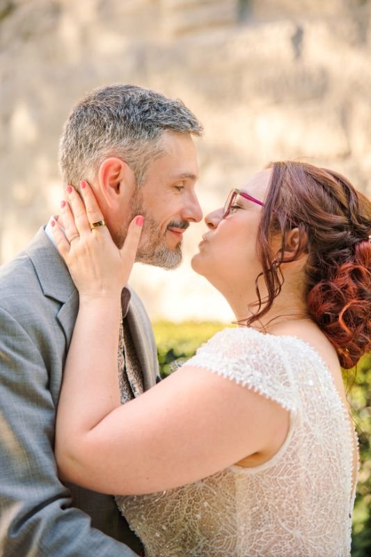 La mariée prend le visage du marié entre ses mains, sur le point de l'embrasser