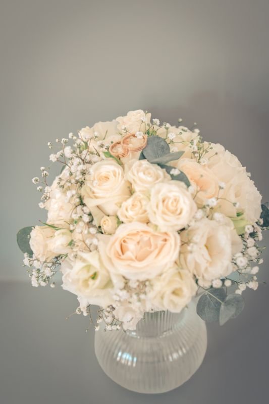 Bouquet de roses blanches et de gypsophile posé dans un vase en verre