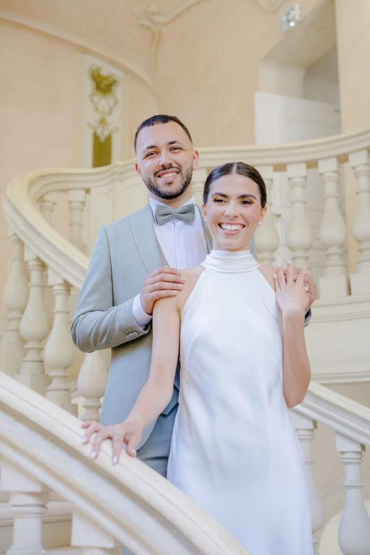 Les mariés souriants dans le grand escalier en pierre d'un château