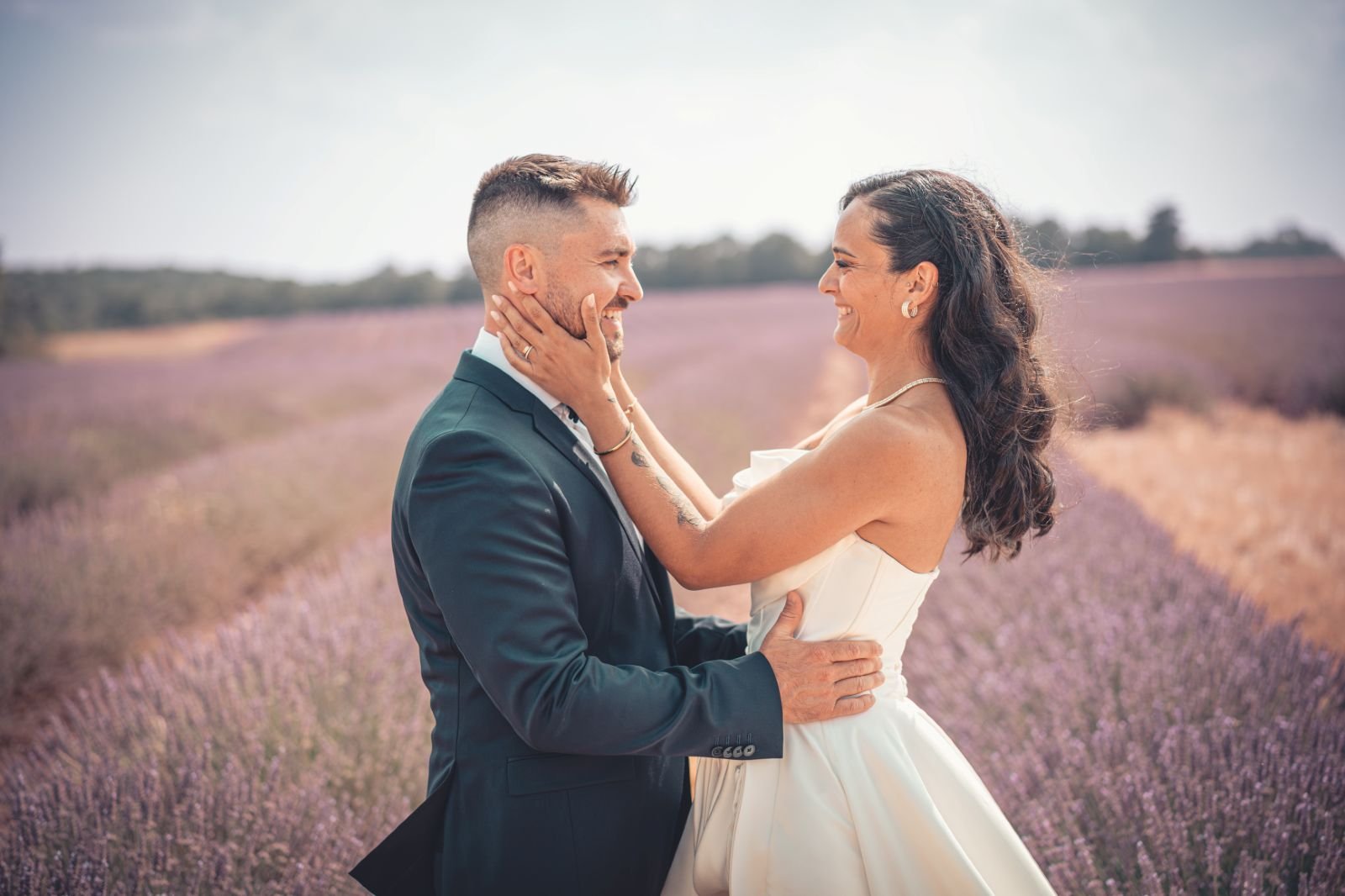 Dans un champ de lavande, la mariée prend tendrement le visage du marié entre ses mains