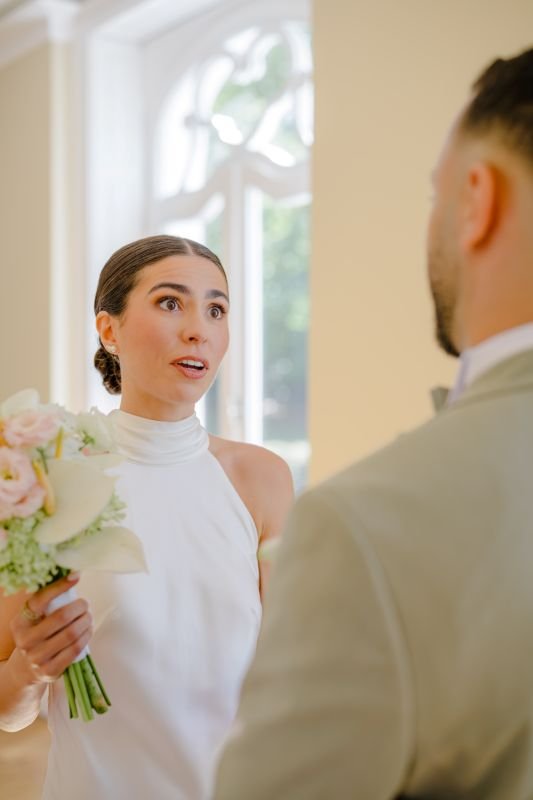 La mariée, bouquet à la main, regarde le marié avec émotion