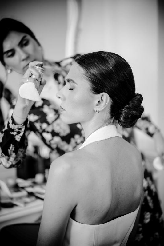 En noir et blanc, la mariée ferme les yeux pendant la fin de son maquillage