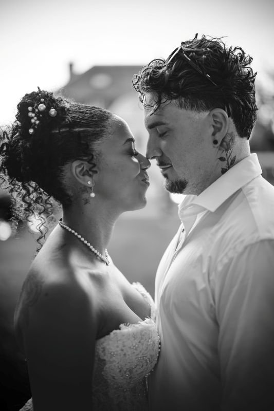 En noir et blanc, les mariés nez à nez, la mariée parée de perles