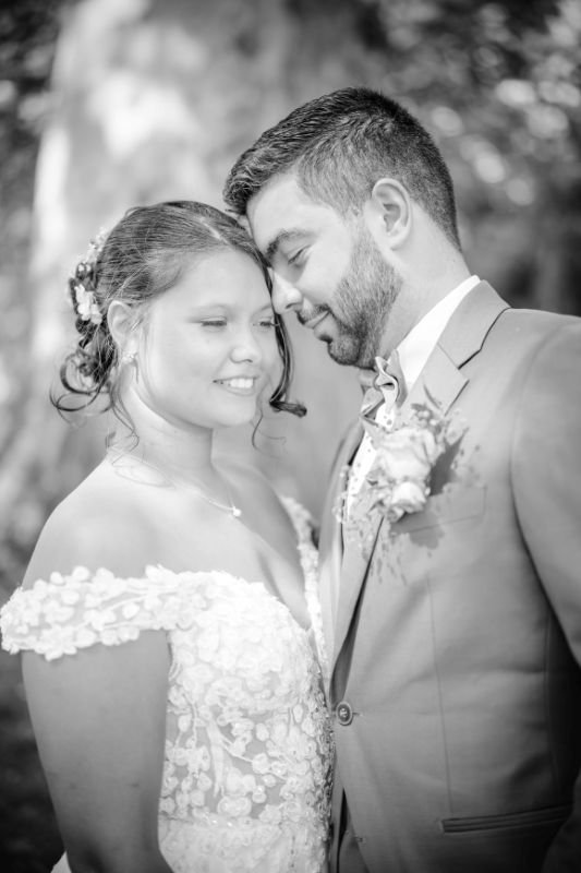 En noir et blanc, le marié pose tendrement son front contre la tempe de la mariée